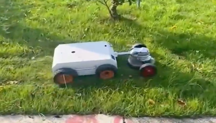 Robot mower trimming edge of lawn near pavement